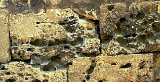 Fragmentierte Zementmörtel im Umfeld der kavernenartig ausgespülten freigelegten - einst durch Kalkschlämmen geschützten - Natursteinoberflächen