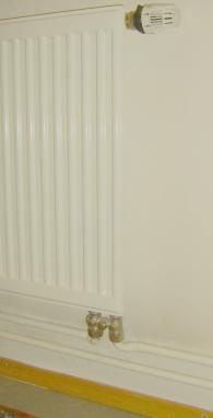 Simple room envelope heating system: Open heating pipes and a additional heat irradiating surface of a flat radiator